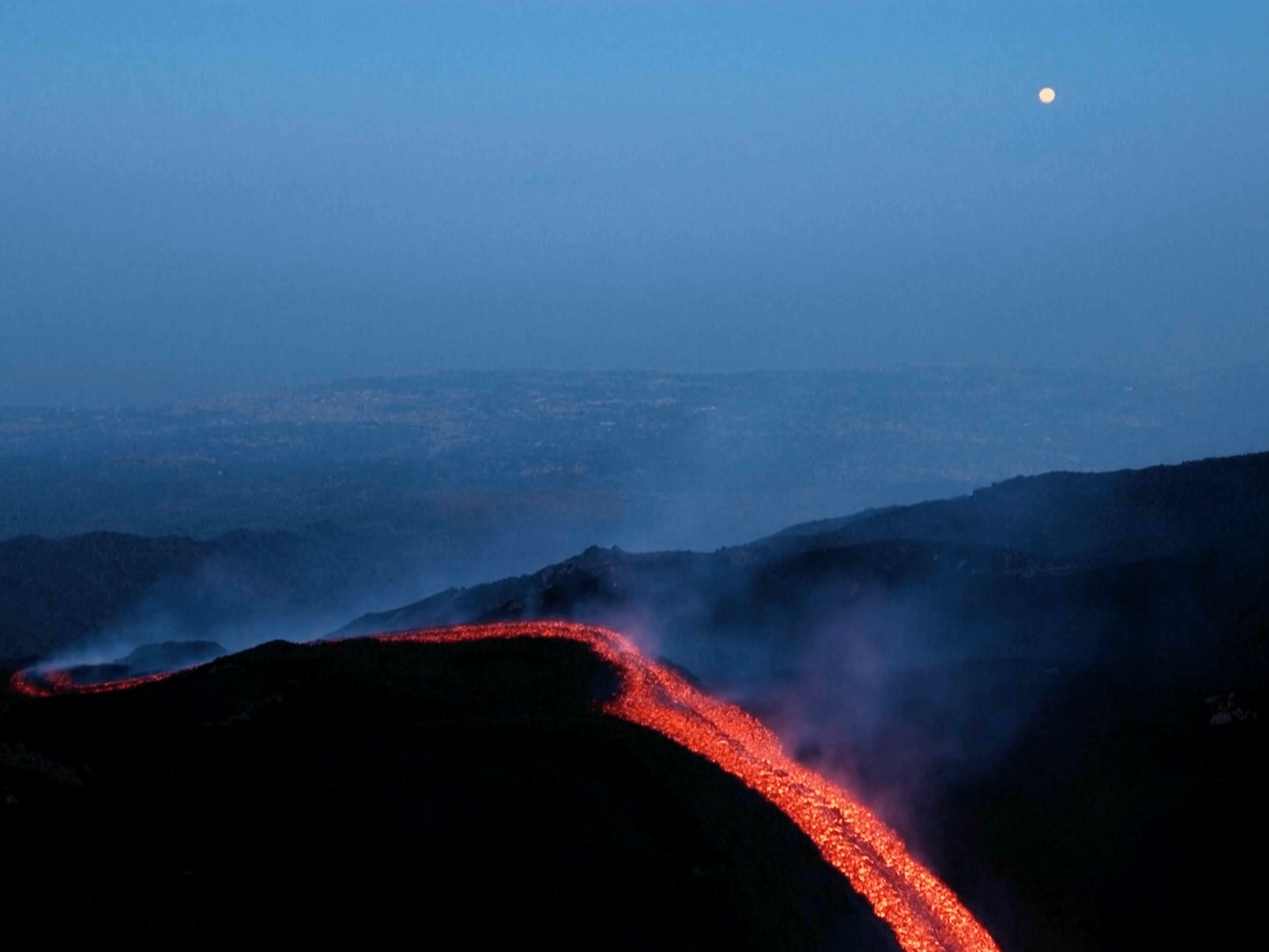 Orange lava flows stream from Mount Etna