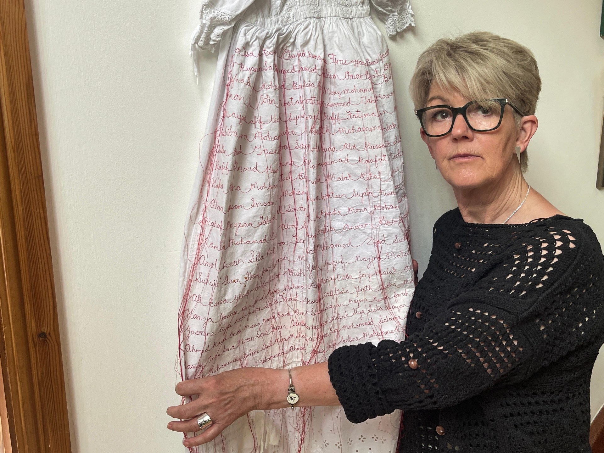 In Wales, an artist sews names of Gaza’s infant victims on christening gown